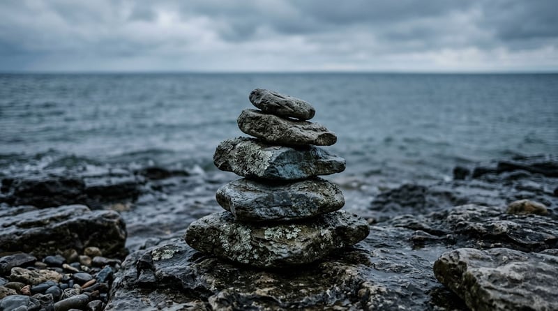Close-up of stacked fieldstones on a rocky Northern Michigan shoreline with soft bay light and muted winter water in the background